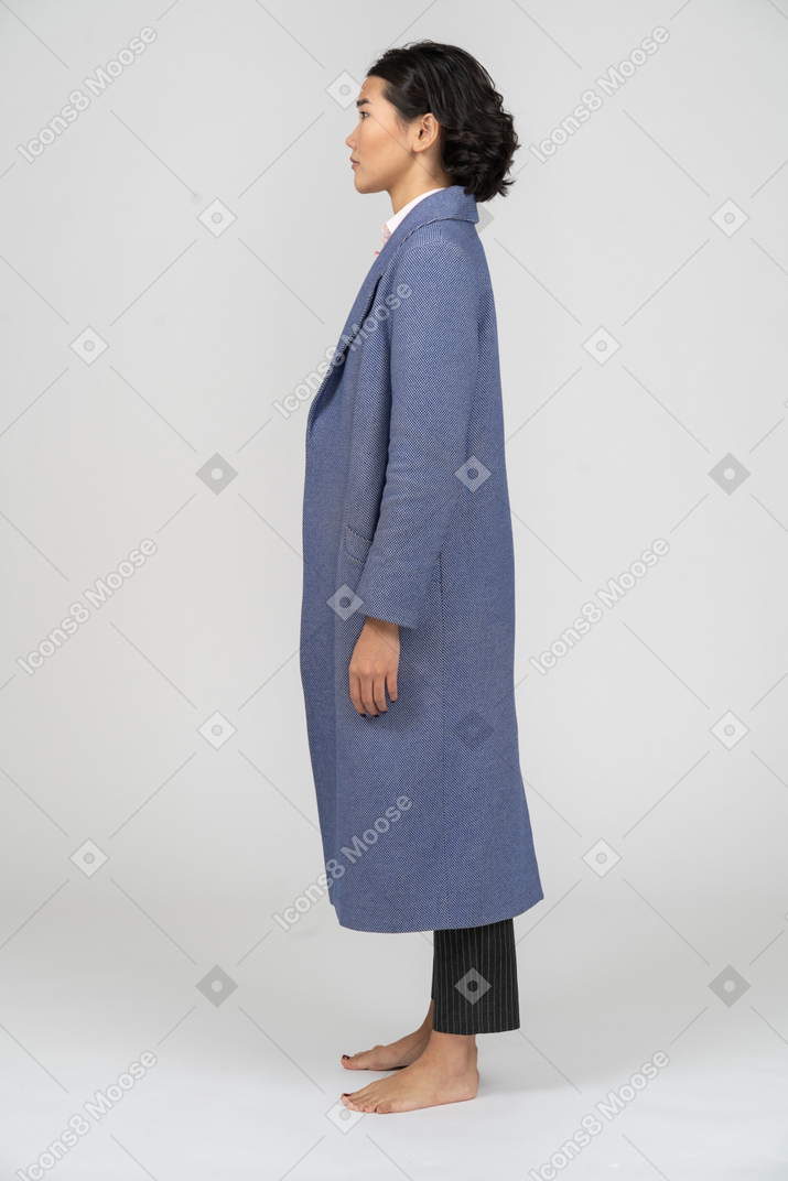 Side view of a woman in blue coat standing