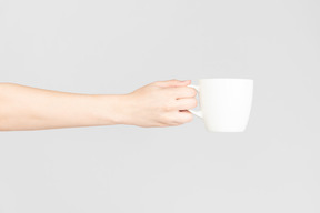 Main féminine tenant une tasse en céramique blanche