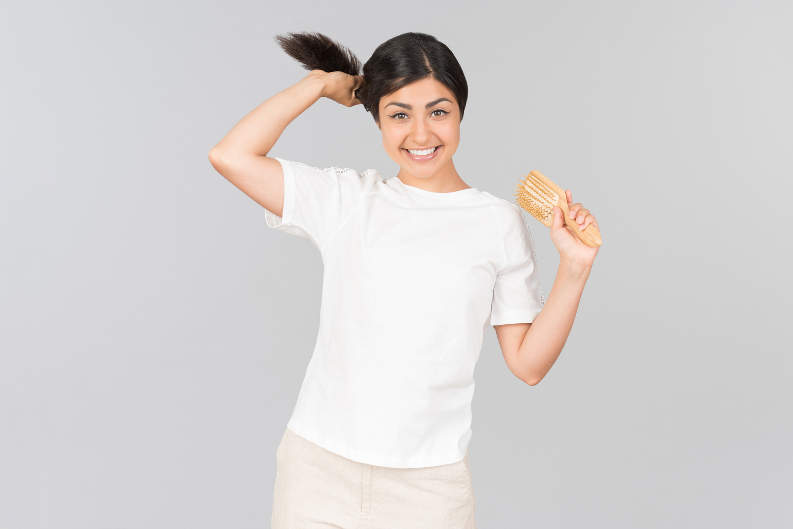 Young indian woman holding her hair and hairbrush