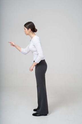 Vista lateral de uma jovem com roupas casuais apontando com um dedo
