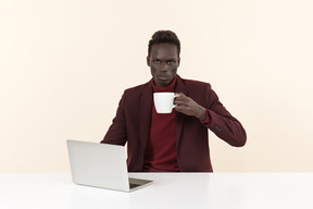 Элегантный темнокожий мужчина сидит за столом в офисе