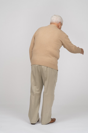Retrovisione di un uomo anziano in abiti casual che dà una mano per scuotere