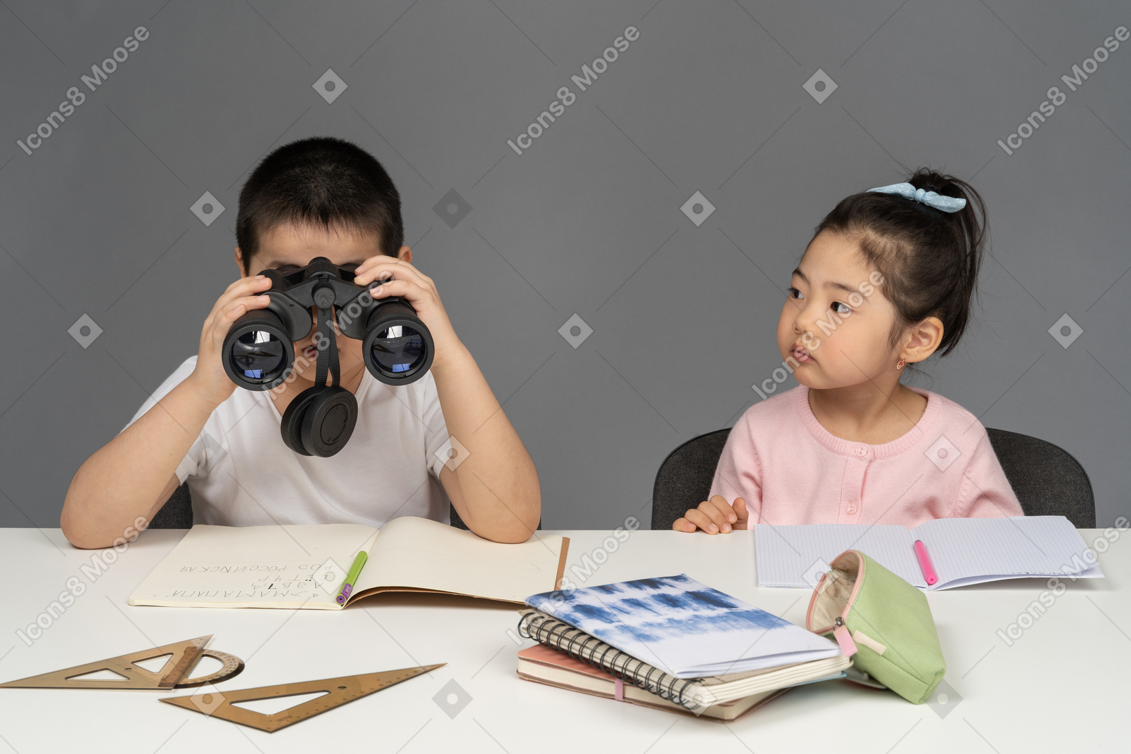 Boy looking through binoculars next to girl