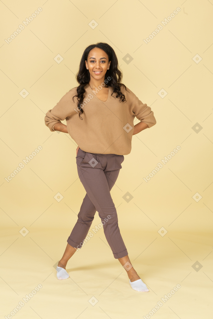 Vista frontal de uma jovem sorridente de pele escura cruzando as pernas