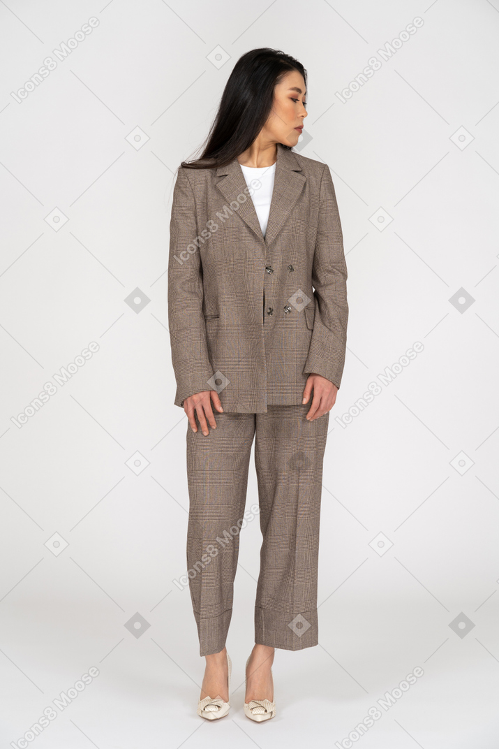 Front view of a young lady in brown business suit looking aside while turning head