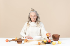 Mulher velha elegante cozinhar um pouco de massa de maçã