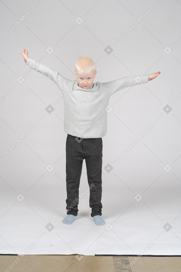Front view of a little boy spreading his arms as if flying