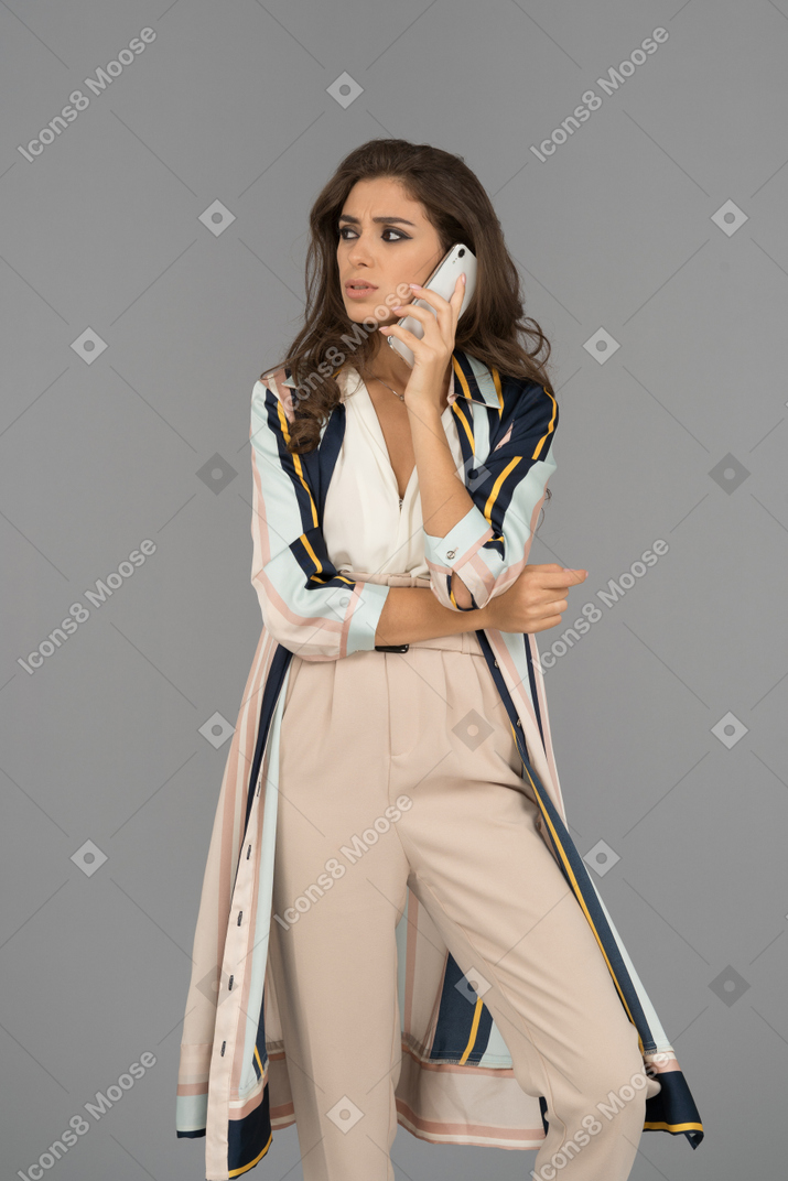 Серьезная ближневосточная женщина стоит с подвижным телефоном и смотрит в сторону