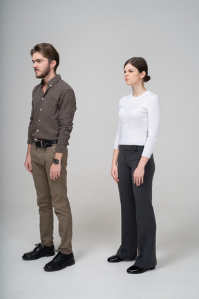 Vista di tre quarti di una giovane coppia scontenta in abbigliamento da ufficio che lavora a maglia le sopracciglia