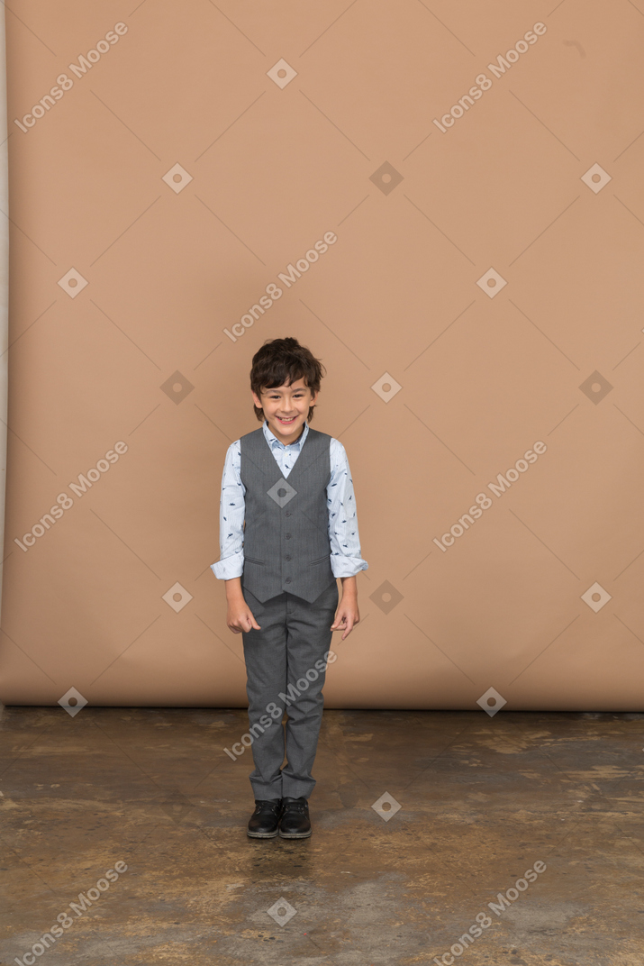 Вид спереди счастливого мальчика в костюме, смотрящего в камеру