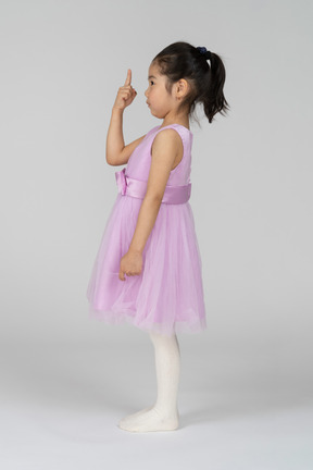 Side view of a little girl pointing upwards