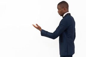 Good-looking man standing in profile and pointing with hand