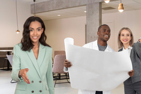 Man and woman discussing project while their colleague welcoming someone