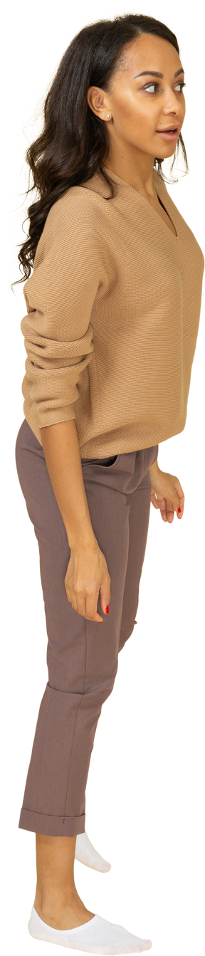 Vista lateral de una curiosa señorita de piel oscura apoyada en su pierna