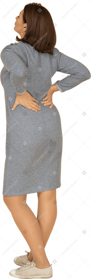 Vista posteriore di una donna in abito grigio in piedi con le mani sui fianchi
