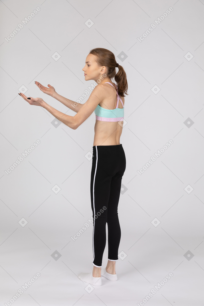 Side view of a surprised teen girl in sportswear raising hands