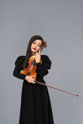 バイオリンを抱きしめる黒のドレスを着た若い女性のクローズ アップ