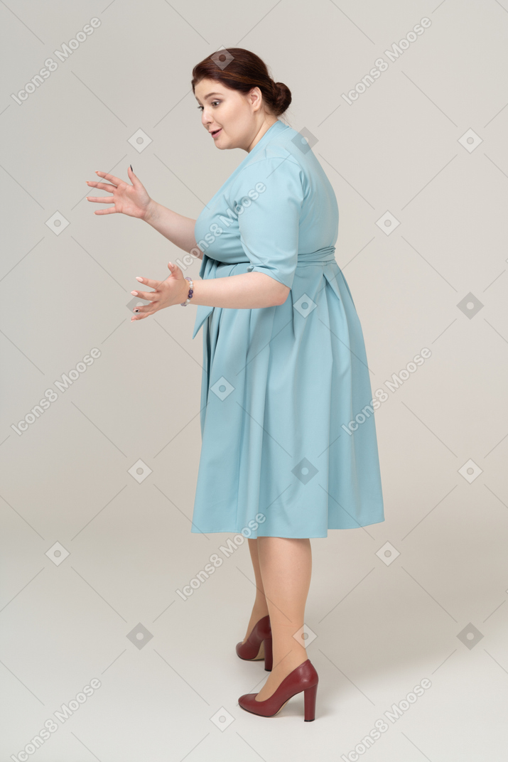Vista lateral de uma mulher de vestido azul mostrando o tamanho de algo