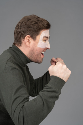 Side view of a screaming male football fan clenching fists