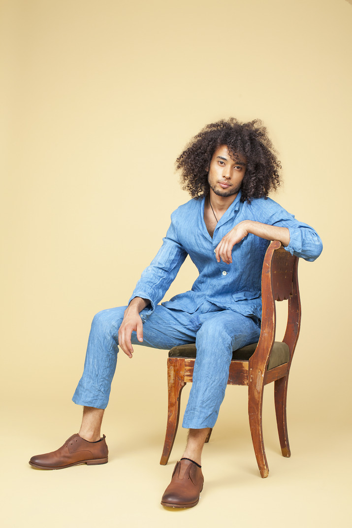 Young man in denim suit sitting on the chair