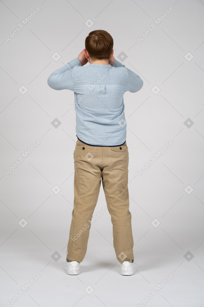 Vista traseira de um menino cobrindo os olhos com as mãos