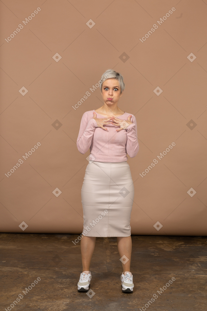 Vista frontal de uma mulher em roupas casuais, estufando as bochechas e olhando para a câmera