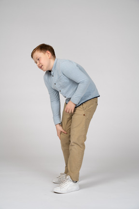 一个男孩弯下腰，触摸受伤的膝盖的侧视图