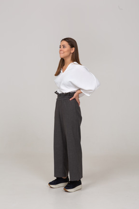 Vue de trois quarts d'une jeune femme en tenue de bureau pressant les lèvres et mettant les mains sur les hanches