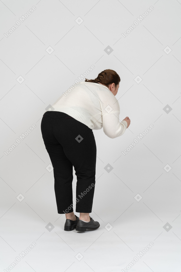 Rear view of a plus size woman in casual clothes bending down