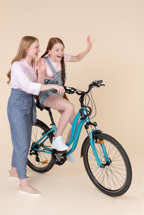 웃는 젊은 여자와 자전거를 타는 십 대 소녀