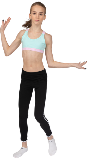 Vista frontal de uma adolescente em roupas esportivas, levantando as mãos e dançando