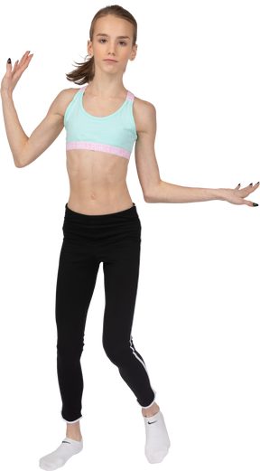 Front view of a teen girl in sportswear raising hands and dancing