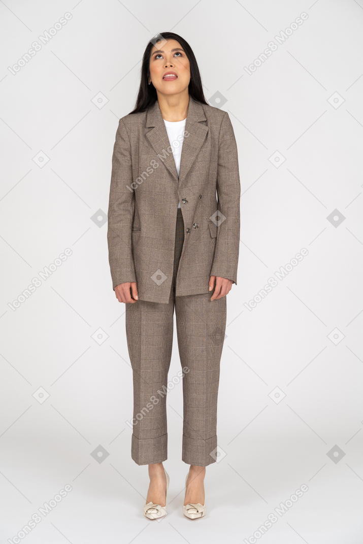 Front view of a bored young lady in brown business suit looking up