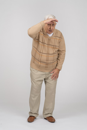 Front view of an old man in casual clothes looking for someone