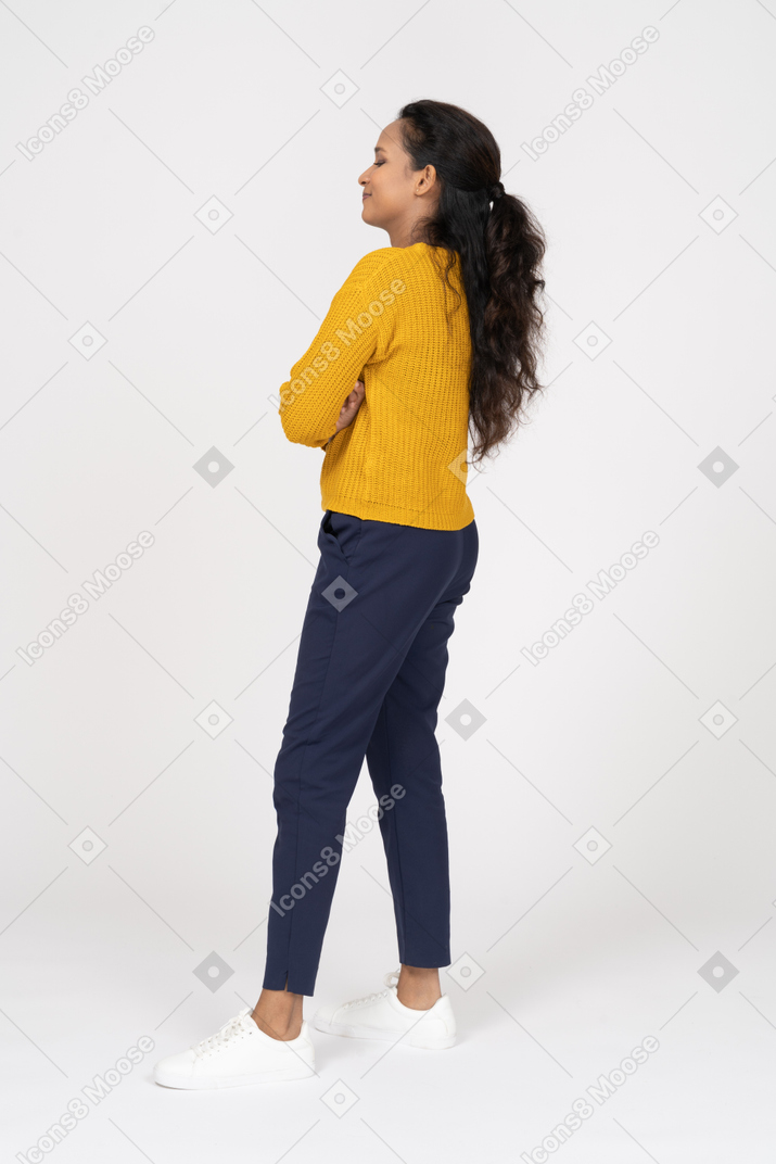Vista lateral de uma garota com roupas casuais posando com os braços cruzados