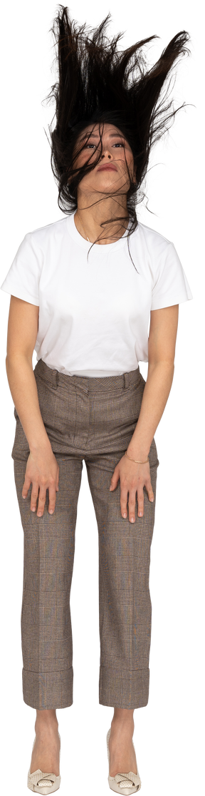 Vista frontale di una giovane donna in calzoni e t-shirt con i capelli disordinati