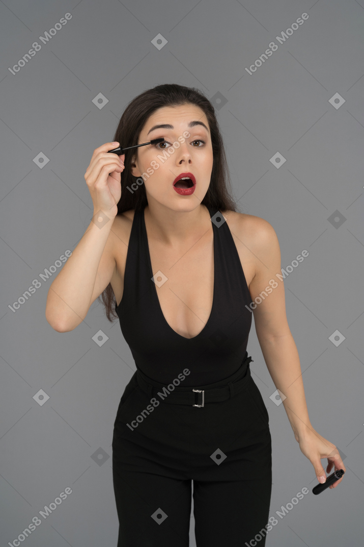 Cheerful young woman applying mascara