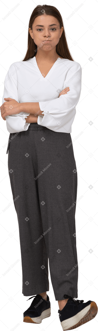 Vista frontal de una joven en ropa de oficina soplando mejillas y cruzando los brazos