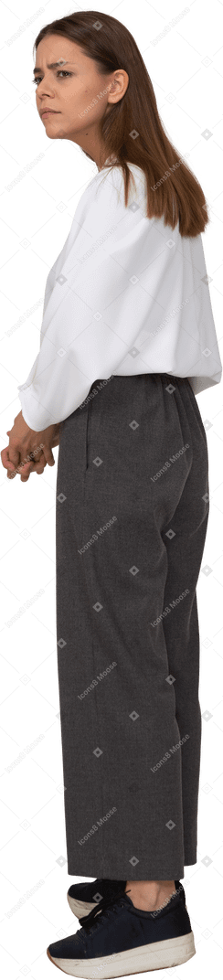 사무복을 입은 젊은 여성이 눈썹을 뜨개질하는 3/4 뒷모습