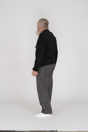 Пожилой мужчина в черном свитере стоит