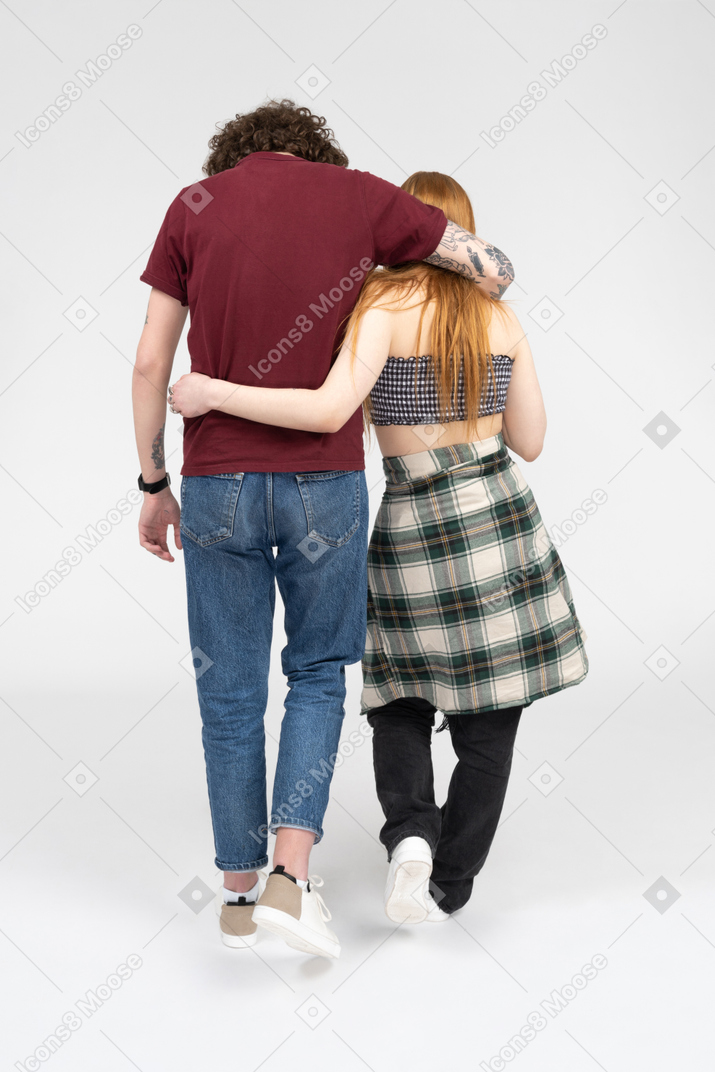 Teenage couple walking with their arms around each other