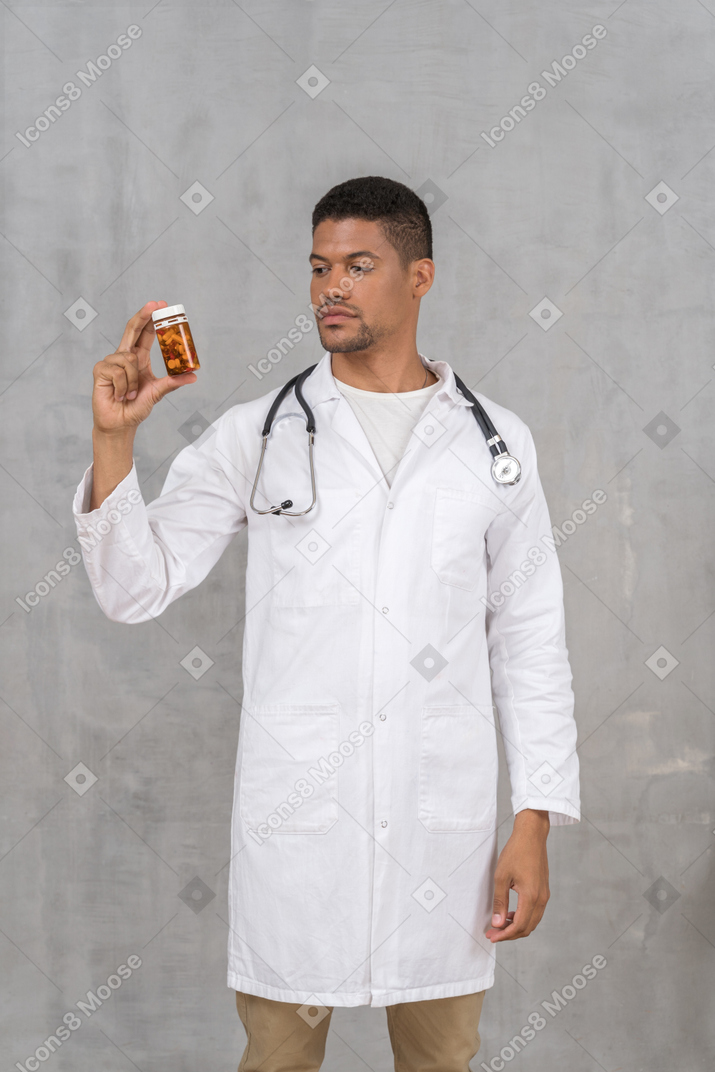 Doctor in lab coat looking at medicine bottle
