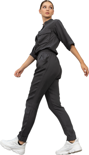 Side view of a walking young woman in a jumpsuit looking aside
