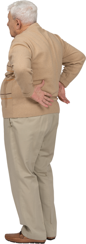 一位身穿休闲服、双手放在背上摆姿势的老人的侧视图