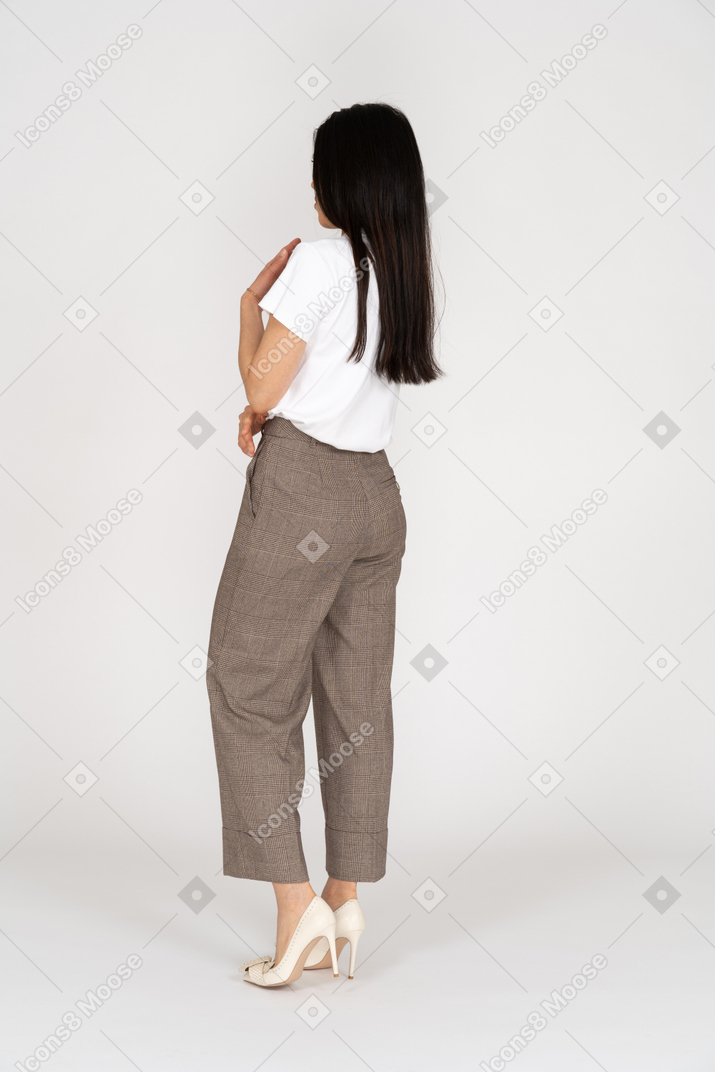 Three-quarter back view of a displeased gesticulating young lady in breeches and t-shirt