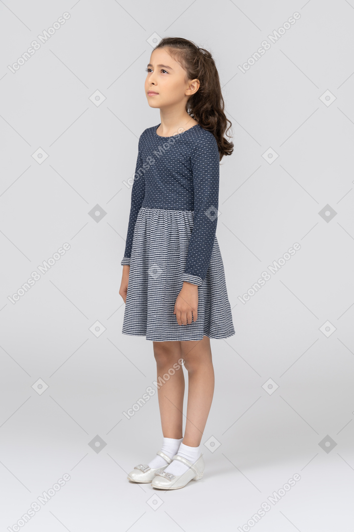 Frowning girl in casual clothes standing with arms at sides