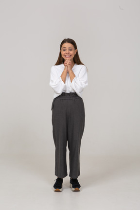 Front view of a pleased young lady in office clothing holding hands together