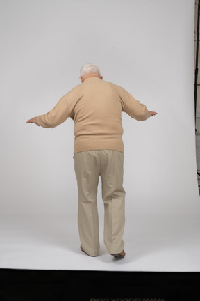 Rear view of an old man in casual clothes walking