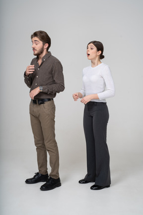 Vista de tres cuartos de una joven pareja estornudando en ropa de oficina