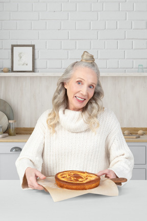 An older woman holding a pie on a plate
